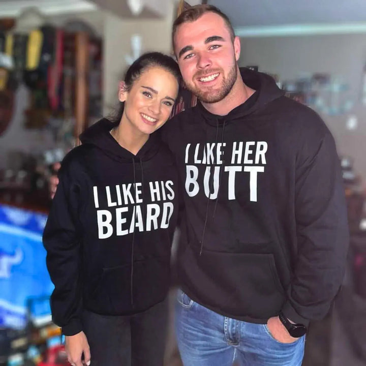 Matching black couple hoodies with bold white text — “I LIKE HER BUTT” on his and “I LIKE HIS BEARD” on hers — from CouplesChoices.com. Fun, flirty, and perfect for couples who love playful, stylish matching outfits.