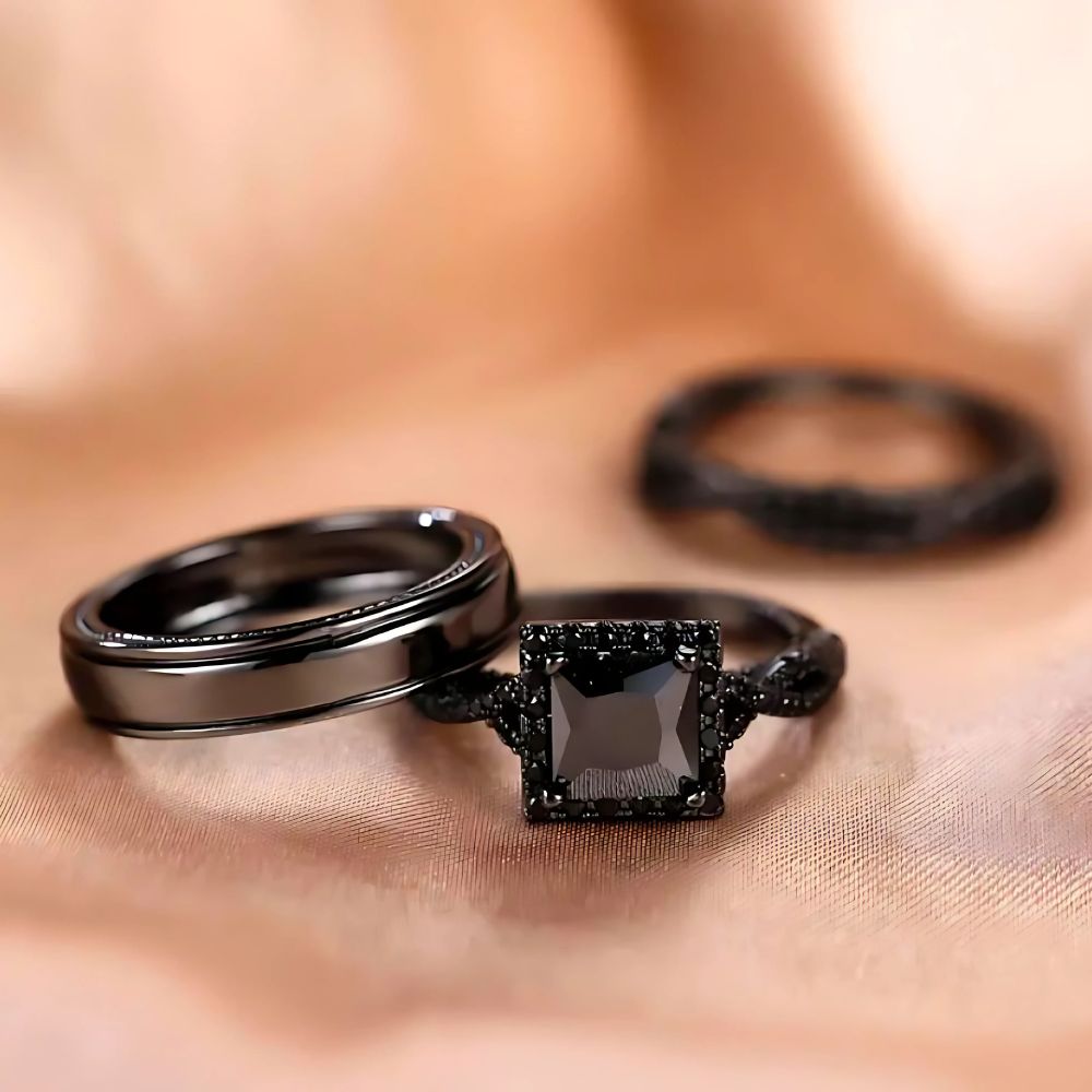 Noir Rings by CouplesChoices.com, featuring a bold black princess-cut engagement ring with pavé black gemstone detailing and matching black tungsten bands—designed to embody elegance, power, and modern romance.