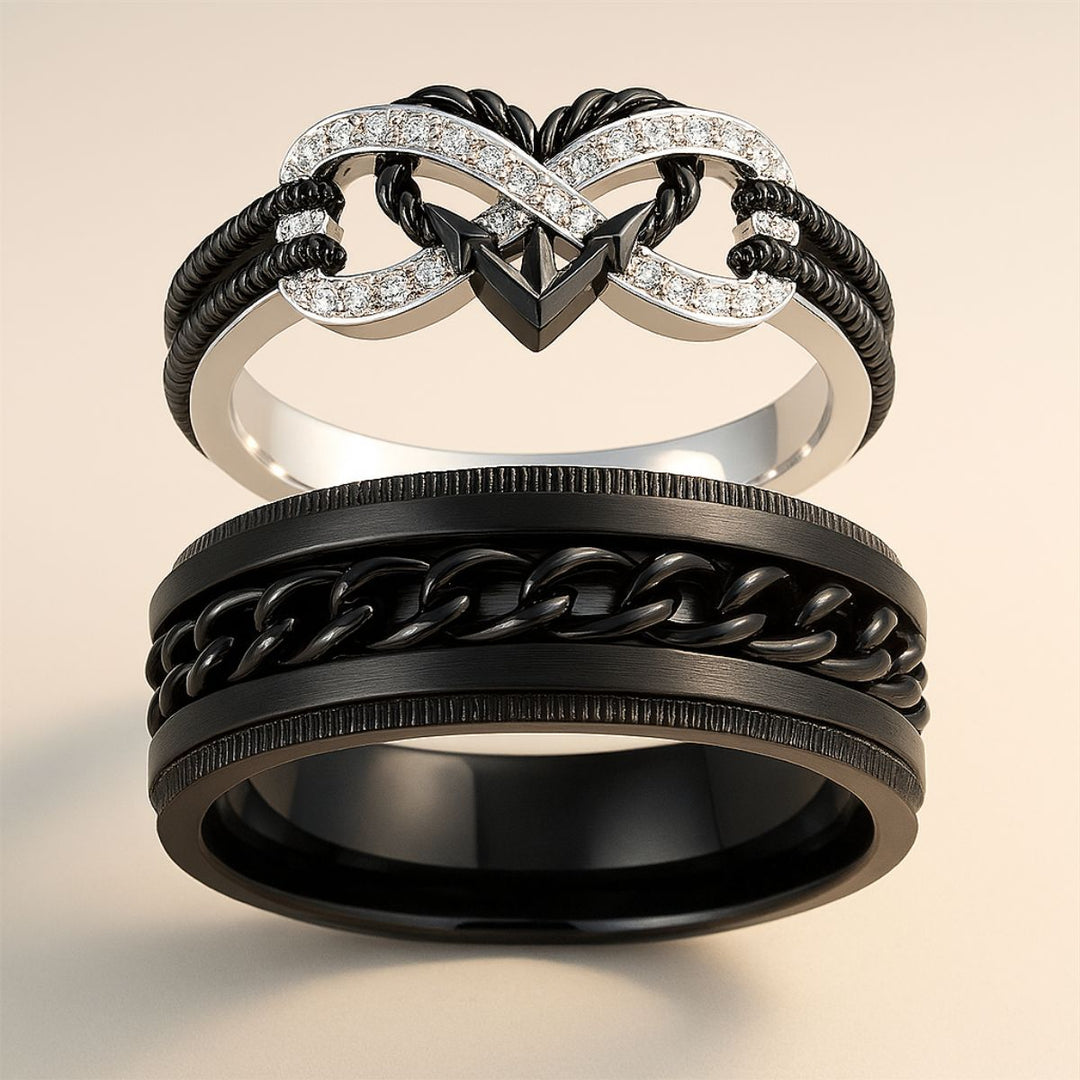 Passion ring set by CouplesChoices.com, featuring a diamond-studded infinity heart with black rope detail and a bold black chain-link men’s band—symbolizing unbreakable, fearless love.