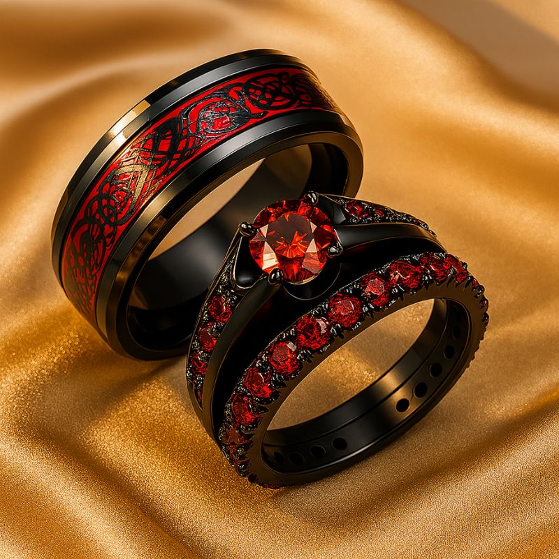 Red Beauty ring set from CouplesChoices.com, featuring a bold black engagement ring with red round-cut center stone and pavé red side stones, paired with a matching eternity band and a black tungsten men’s ring with engraved red Celtic inlay.