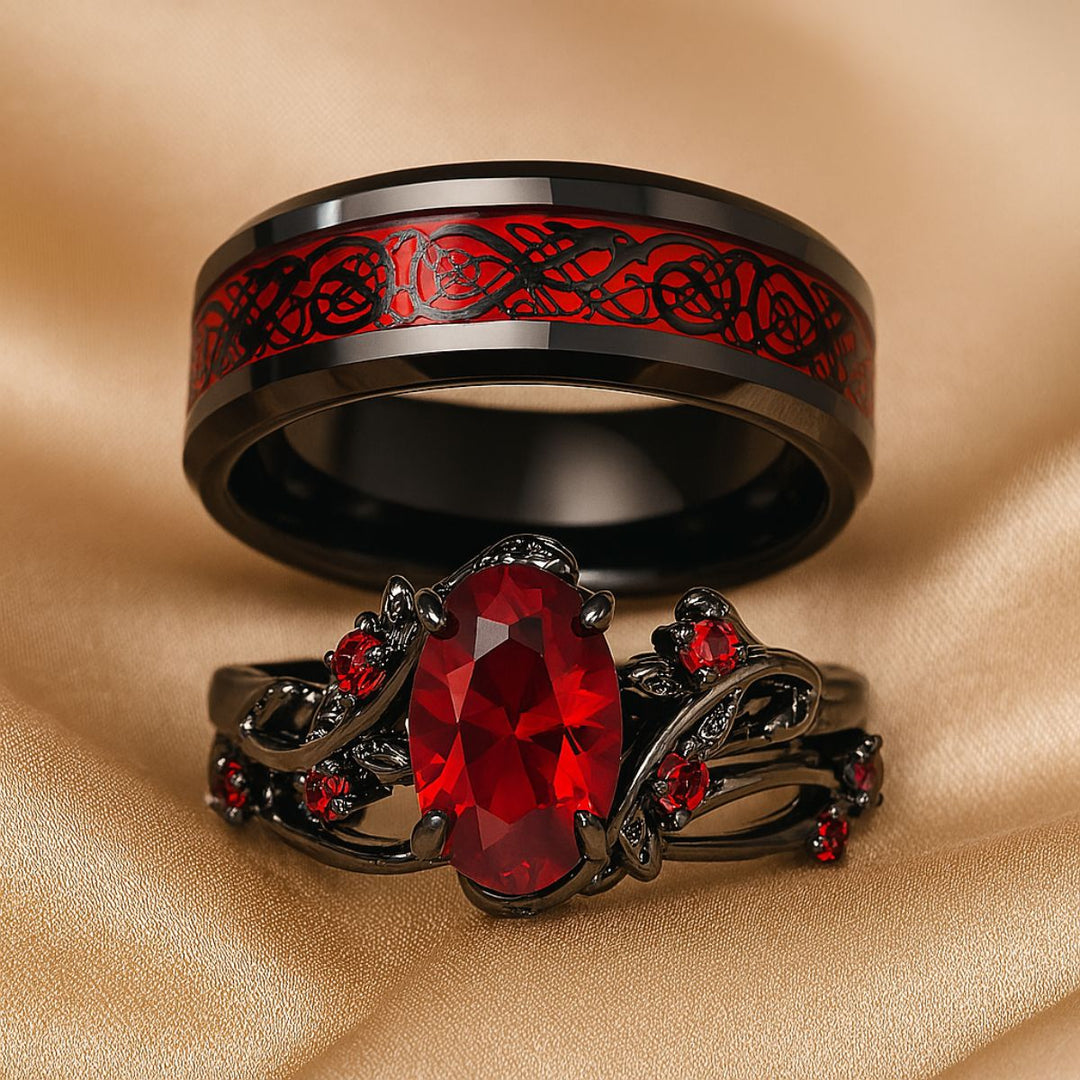 Red Heart wedding ring set from CouplesChoices.com, featuring a black tungsten men’s band with Celtic red inlay and a matching women’s ring with an oval-cut ruby centerpiece and vine-inspired black setting.