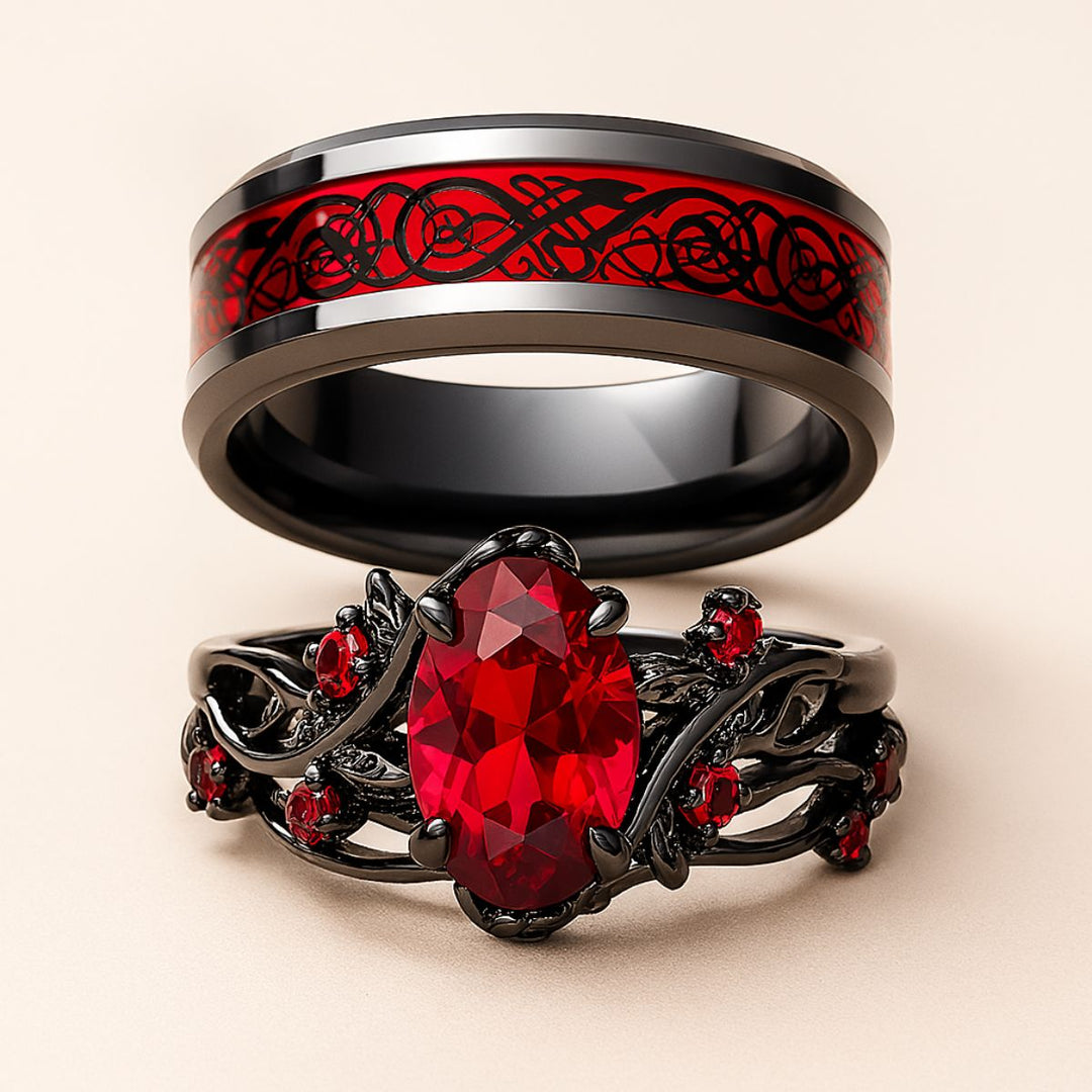 Red Heart wedding ring set from CouplesChoices.com, featuring a black tungsten men’s band with Celtic red inlay and a matching women’s ring with an oval-cut ruby centerpiece and vine-inspired black setting.