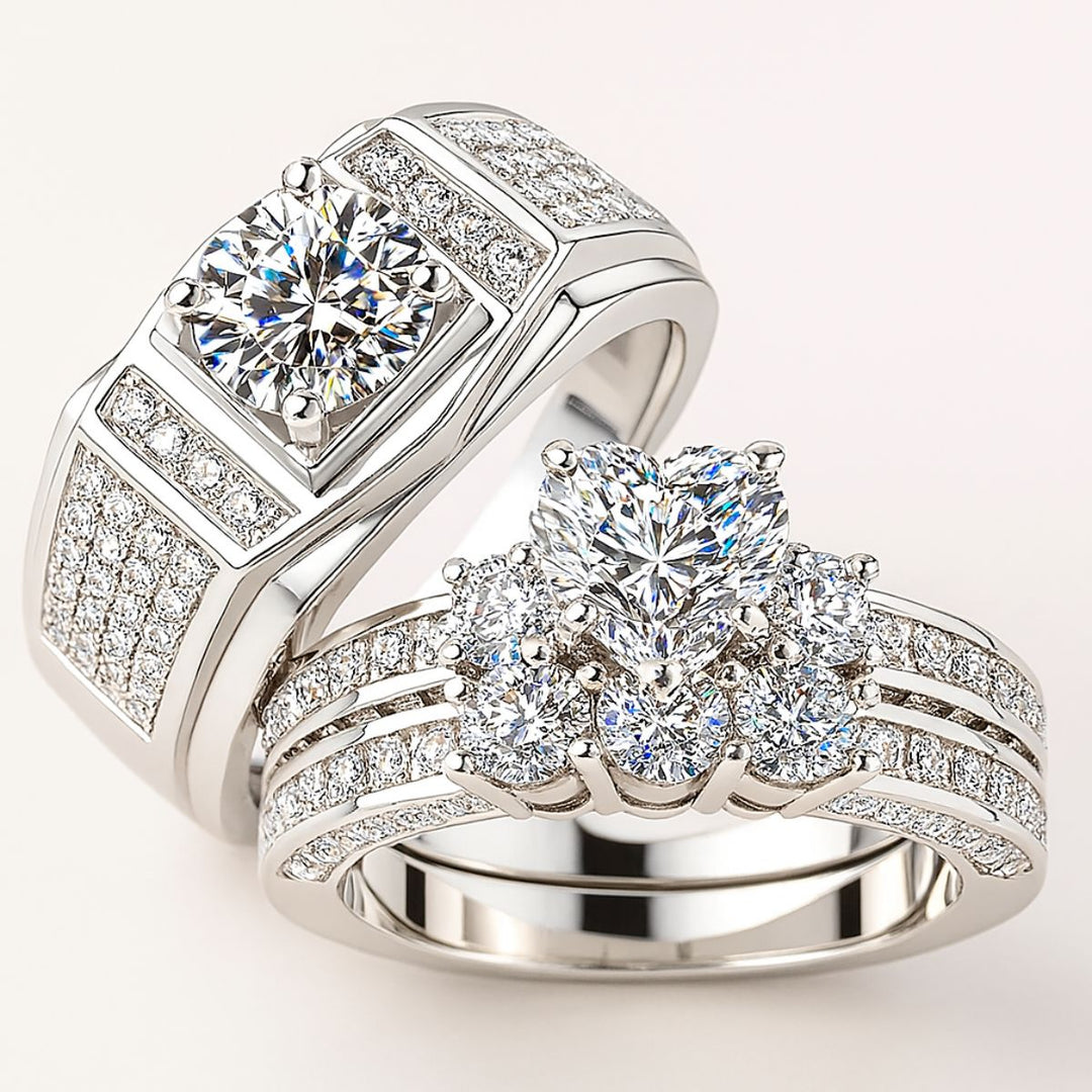 Spring Heart wedding ring set from CouplesChoices.com, featuring a heart-shaped center stone with pavé diamonds on a triple-row band, paired with a men’s ring with a round-cut center and pavé-set accents in platinum finish.