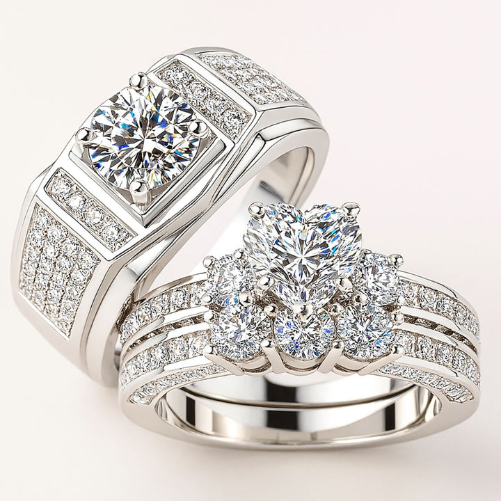 Spring Heart wedding ring set from CouplesChoices.com, featuring a heart-shaped center stone with pavé diamonds on a triple-row band, paired with a men’s ring with a round-cut center and pavé-set accents in platinum finish.