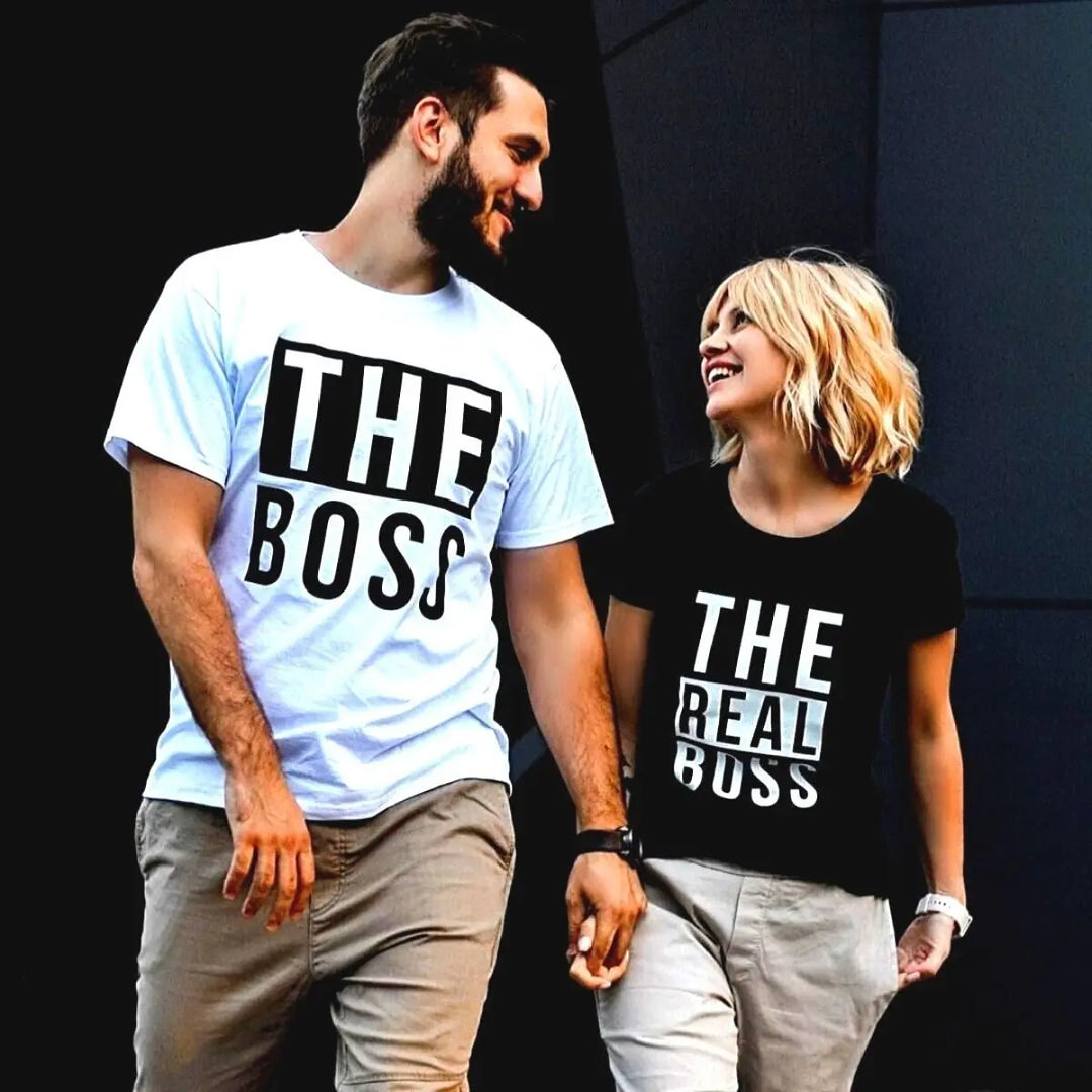 Couples matching graphic tees from CouplesChoices.com—his reads “THE BOSS” in bold black on white, hers says “THE REAL BOSS” in bold white on black. A playful and confident way to show off relationship dynamics with style.