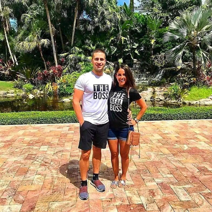 Couples matching graphic tees from CouplesChoices.com—his reads “THE BOSS” in bold black on white, hers says “THE REAL BOSS” in bold white on black. A playful and confident way to show off relationship dynamics with style.