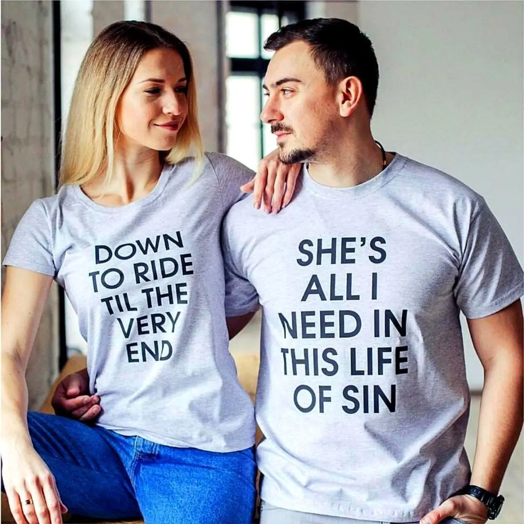 Couples’ matching grey tees with bold black text—his reads ‘She’s all I need in this life of sin,’ hers says ‘Down to ride til the very end.’ A fearless, ride-or-die statement set from CouplesChoices.com.