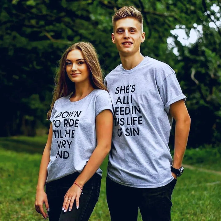 Couples’ matching grey tees with bold black text—his reads ‘She’s all I need in this life of sin,’ hers says ‘Down to ride til the very end.’ A fearless, ride-or-die statement set from CouplesChoices.com.
