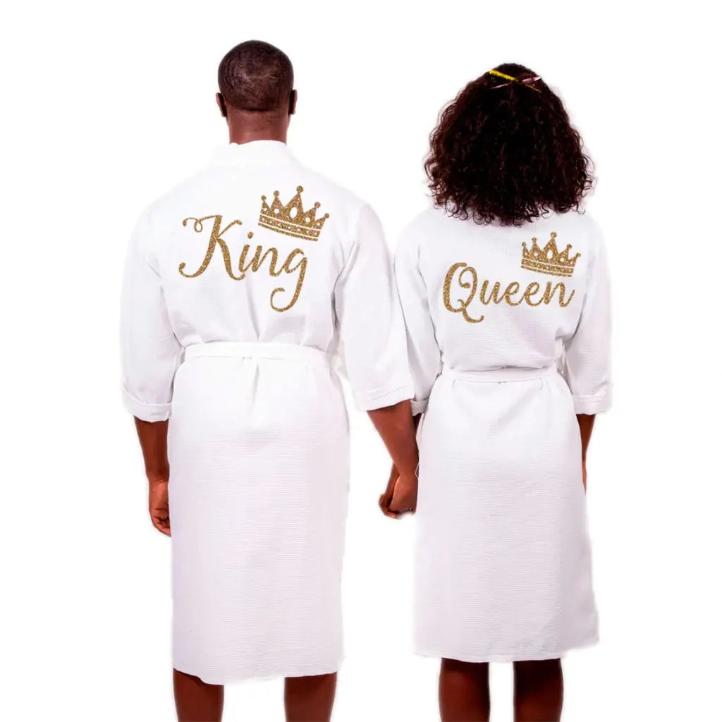 Couples wearing matching white waffle-knit cotton robes featuring gold embroidered “King” and “Queen” with crown motifs, showcasing elegant, coordinated loungewear designed for comfort, romance, and luxury by CouplesChoices.com.